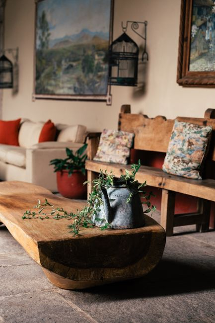 Home Cozy rustic living room featuring wooden furniture, decorative pillows, and a vintage metal watering can with vines.