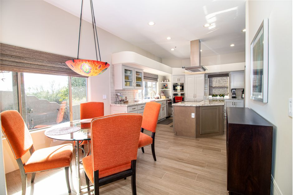 A contemporary kitchen and dining room with vivid orange chairs and stylish decor.